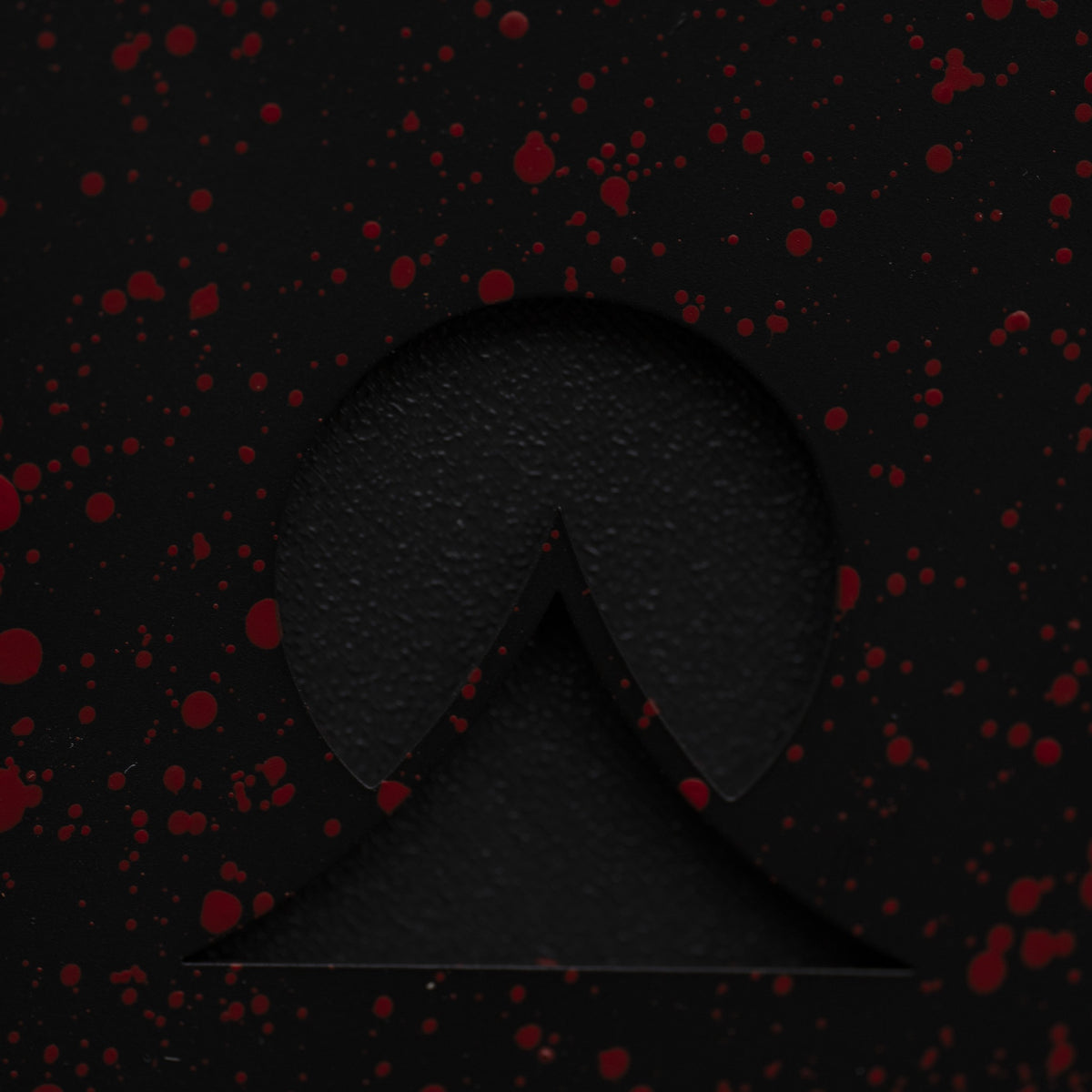 Close-up of the Ohma logo under red splatter on black paint