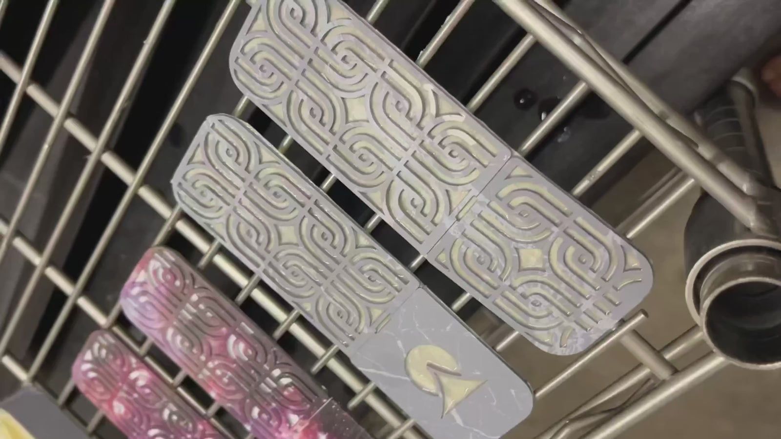 Hydro dipped parts drying on a rack and paint swirling on the water